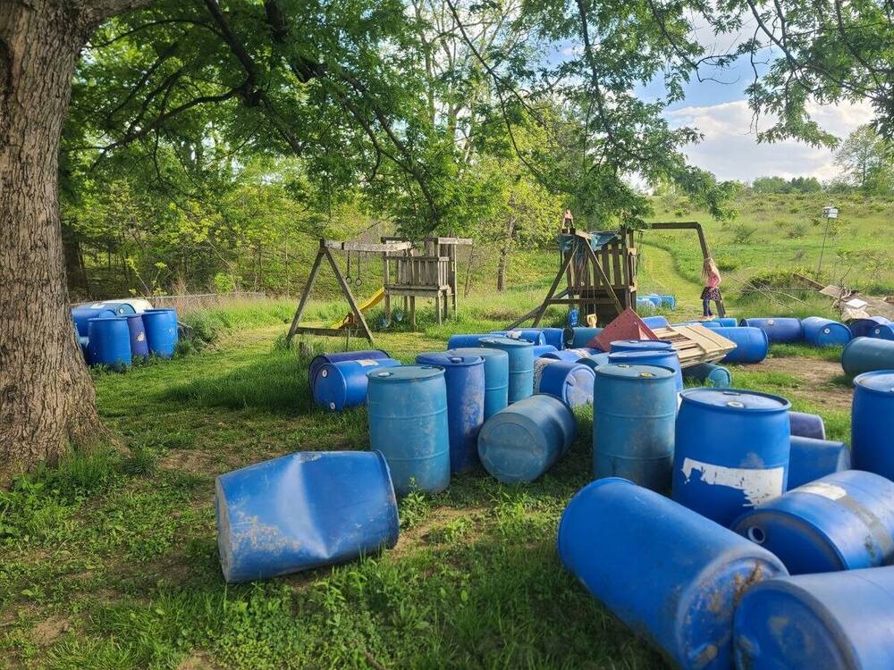 Before: Backyard cluttered with scattered blue barrels and debris